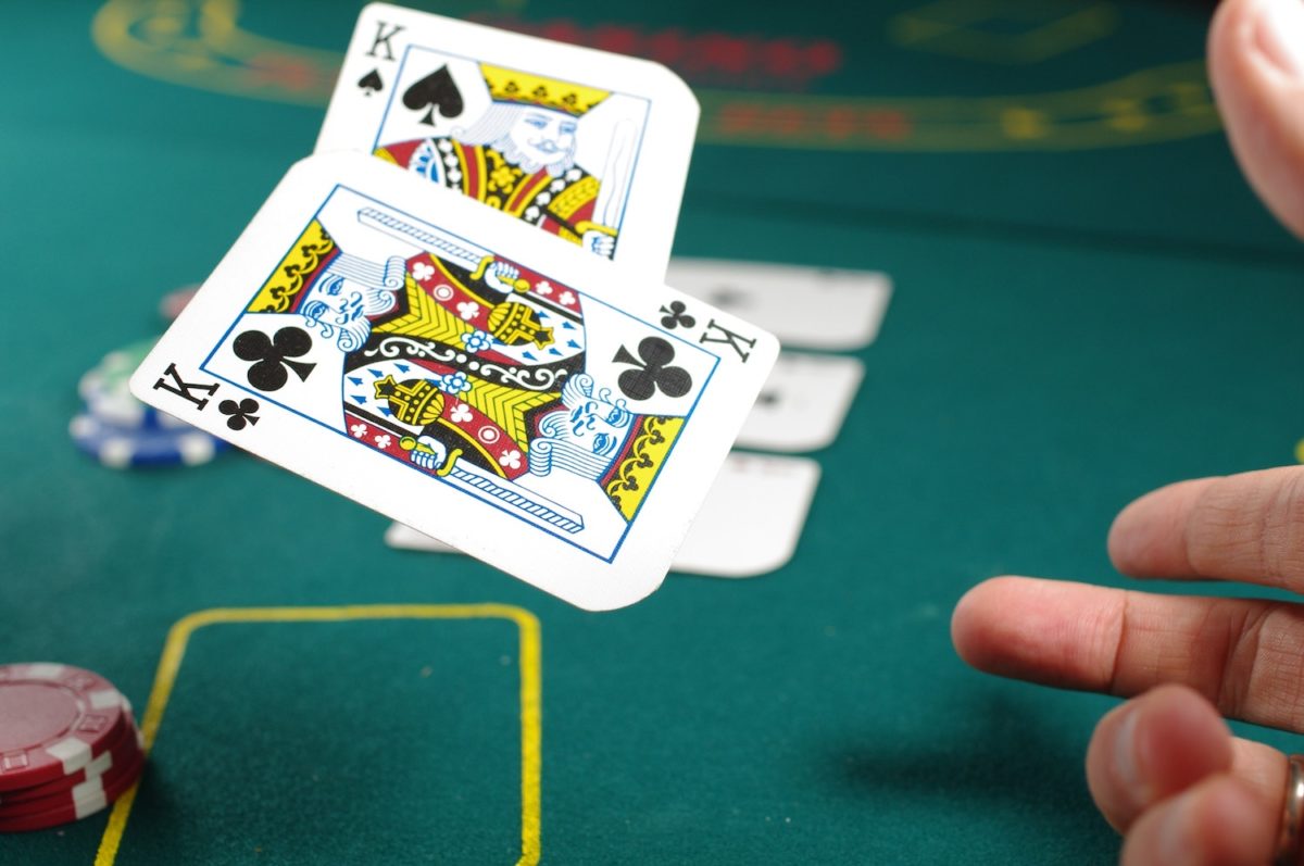Kartenspiel im Casino mit einigen Jetons im Hintergrund.