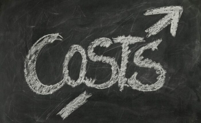 Das Wort 'Costs' mit einem Pfeil nach oben ist in Kreide auf einer Schultafel gezeichnet.