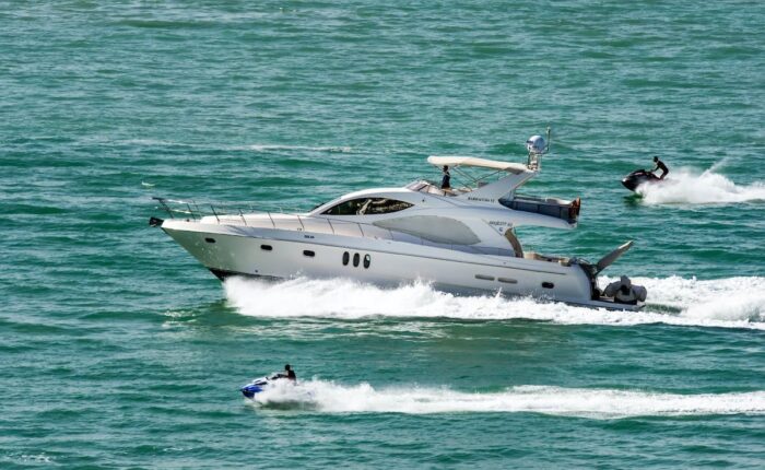 Luxusyacht fährt auf offenem Meer, begleitet von zwei Jetskis.
